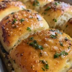 Juicy garlic bread rolls with visible garlic bits and herb sprinkles.