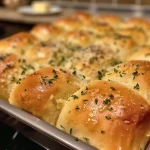 Side view of warm garlic butter dinner rolls, glistening with melted butter.