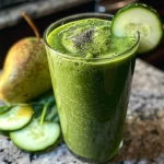 Fresh green smoothie made with avocado and apple, garnished with a lime wedge.