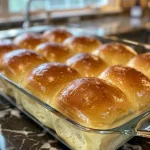 Juicy, freshly baked yeast rolls glistening with butter, highlighting their fluffy texture.