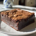 A side perspective of a decadent brownie, highlighting its fudgy interior and golden brown edges.
