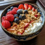 Colorful Greek yogurt breakfast bowl featuring mixed berries and crunchy granola.
