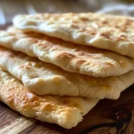 Juicy and warm pita bread resting on a wooden cutting board.