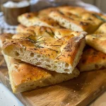 Juicy sourdough focaccia showcasing its airy texture and aromatic rosemary garnish.