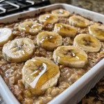 Detailed view of baked oatmeal featuring ripe banana pieces, served in a cozy kitchen setting.