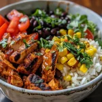 A close-up side view of Chipotle Chicken Bowls featuring grilled chicken, black beans, and cilantro lime rice.
