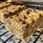 Close-up view of golden-brown banana peanut butter oatmeal bars with chocolate chips.