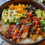 Side view of a delicious BBQ chicken rice bowl layered with cheese and crispy onions.
