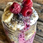 A close-up side view of Berry Protein Overnight Oats in a glass jar, showcasing layers of oats, berries, and yogurt.