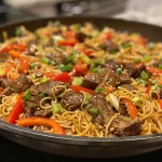 Close-up view of a colorful beef lo mein stir fry with beef, vegetables, and noodles.