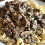 Close-up view of a plate of Healthy Beef Stroganoff with creamy sauce and garnished with parsley.