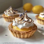 Lemon Lavender Meringue Tartlets arranged elegantly on a white plate, showcasing their glossy meringue.