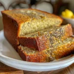 A slice of Lemon Poppy Seed Loaf revealing poppy seeds and a light lemon drizzle on top.