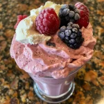 Close-up view of a vibrant mixed berry cheesecake smoothie with a creamy texture.