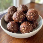 Close-up side view of no-bake brownie protein bites on a wooden surface.