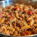 Side view of a vibrant one-pot beefy tomato pasta meal, highlighting the mix of pasta, beef, and tomatoes.
