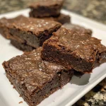 Close-up view of a delicious protein brownie bite resting on a rustic wooden surface.