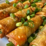 Close-up of crispy spring rolls filled with colorful vegetables on a plate.