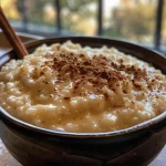 A close-up image of creamy stovetop rice pudding in a bowl, sprinkled with cinnamon.