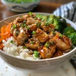Close-up view of a teriyaki chicken rice bowl with colorful vegetables.