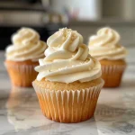 Close-up side view of decorated vanilla cupcakes with creamy frosting.