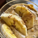 ['Close-up view of a creamy Banana Almond Butter smoothie in a glass, with banana slices on top.', 'Side view of a vibrant Banana Almond Butter Energy Booster, showcasing its thick texture and garnished with almonds.', 'Image of a blended Banana Almond Butter drink in a clear glass, featuring a sprinkle of cinnamon on the surface.', 'A refreshing smoothie made with banana and almond butter, captured in a close-up shot.']