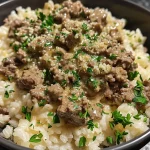 ['Close-up view of a bowl filled with creamy garlic butter beef and rice topped with cheddar cheese.', 'A delicious serving of creamy garlic butter beef and rice, showcasing melted cheese and garnished with parsley.', 'Side view of a plate of creamy garlic butter beef and rice, featuring ground beef and a rich buttery sauce.', 'Juicy creamy garlic butter beef and rice with a sprinkle of grated Parmesan and chopped parsley on top.']