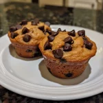 ['Close-up view of Greek yogurt chocolate chip muffins with melting chocolate chips.', 'Side view of delicious Greek yogurt muffins, featuring chocolate chips and a golden-brown crust.', 'Juicy Greek yogurt chocolate chip muffins showcased in a close-up shot, highlighting their texture.', 'Succulent Greek yogurt muffins with chocolate chips, captured from the side to emphasize their fluffiness.']
