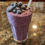 ['Close-up shot of a refreshing vanilla blueberry protein shake in a glass.', 'Side view of a protein shake filled with blueberries and a creamy texture.', 'A vibrant vanilla blueberry shake with a smooth consistency in a clear cup.', 'Delicious looking protein shake made with blueberries, presented in a glass.']