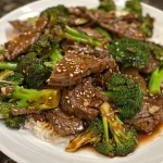 ['Close-up view of a juicy beef and broccoli stir-fry served in a bowl.', 'Side view of tender beef slices and bright green broccoli in a savory sauce.', 'A colorful plate featuring beef sirloin and broccoli stir-fried with garlic and ginger.', 'Detailed image of flavorful beef and broccoli with vibrant colors and textures.']