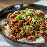 ['Close-up of a bowl filled with crispy ground beef, fluffy rice, and vibrant green onions in creamy broth.', 'Side view of a delicious dish featuring crispy ground beef and rice in a creamy gochujang broth, garnished with sliced cucumbers.', 'Juicy ground beef and rice with a rich gochujang broth, topped with sesame seeds and green onions.', 'A close-up of a savory bowl of crispy ground beef and rice, presented in a creamy red broth.']