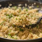['A close-up view of fluffy garlic butter quinoa garnished with herbs.', 'A side view of a bowl filled with garlic butter quinoa, showcasing its texture.', 'Juicy garlic butter quinoa served in a dish, with a sprinkle of seasoning on top.', 'A detailed image of quinoa mixed with garlic butter, highlighting its golden color.']
