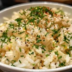 ['Close-up view of garlic butter rice with a golden hue and herbs sprinkled on top.', 'A side view of fluffy garlic butter rice, showcasing its rich color and texture.', 'Juicy garlic butter rice garnished with parsley and chives, captured in natural light.', 'A detailed angle of buttered rice mixed with garlic and spices, emphasizing its freshness.']