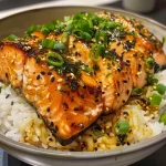 ['A close-up view of a Garlic Butter Salmon Rice Bowl with vibrant colors and textures.', 'Juicy salmon fillets on a bed of rice, garnished with green onions and sesame seeds.', 'A delicious bowl featuring tender garlic butter salmon, rice, and optional toppings.', 'A side view of a colorful rice bowl showcasing salmon and fresh ingredients.']