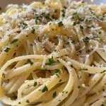 ['Close-up view of garlic buttered noodles topped with grated Parmesan and parsley.', 'A delectable plate of garlic buttered pasta with melted butter glistening on top.', 'A side view of a bowl filled with buttery garlic noodles and sprinkled Parmesan cheese.', 'Delicious garlic buttered noodles served in a bowl, showcasing their creamy texture.']