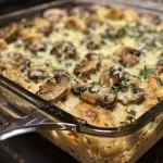 ['Close-up of a high protein keto garlic mushroom chicken casserole with melted cheese on top.', 'Side view of a creamy garlic mushroom chicken casserole garnished with spinach and cheese.', 'Juicy chicken casserole with mushrooms and a golden cheese layer, served hot.', 'High protein casserole featuring chicken, garlic, and mushrooms, showcased in a baking dish.']