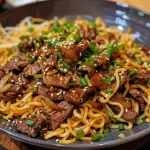 ['Close-up view of a plate filled with honey soy crispy beef and noodles topped with spring onions.', 'Side view of juicy honey soy crispy beef and noodles on a rustic plate.', 'Appetizing dish featuring crispy beef drenched in honey soy sauce served over noodles.', 'Close-up of delicious honey soy beef and noodles garnished with sliced spring onions.']