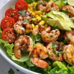 ['Close-up of a vibrant Zesty Honey Lime Shrimp Salad with shrimp, avocado, and cherry tomatoes.', 'Colorful salad featuring grilled shrimp, fresh lettuce, and lime dressing, captured side view.', 'Detail shot of a refreshing shrimp salad with lime, avocado, and tomatoes on a plate.', 'Close-up image of a summer shrimp salad with bright vegetables and a honey lime glaze.']