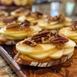 Close-up view of crostini topped with brie, apple slices, and honey.