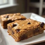 A side view of gooey brown butter chocolate chip blondies with a golden crust.