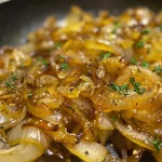 Close-up view of caramelized onions glistening in a skillet.