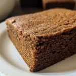A close-up side view of a juicy gingerbread cake, showcasing its moist texture and rich color.