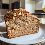 Close-up side view of a moist apple pecan bread loaf, showcasing its texture and ingredients.