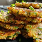 A close-up view of golden-brown vegan zucchini fritters, lightly crispy on the edges.