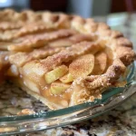 A close-up side view of a freshly baked Honeycrisp apple pie with a golden crust.