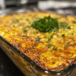 Close-up of a golden-brown Jiffy Corn Casserole in a dish, highlighting its moist texture.