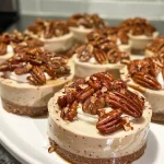 A creamy no-bake cheesecake topped with pecans and whipped cream in a glass dessert dish.