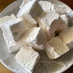 Close-up of fluffy protein marshmallows dusted with powdered sugar.