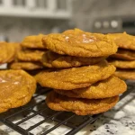 Side view of a plate of pumpkin cookies topped with cream cheese frosting.