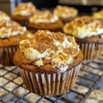 Close-up side view of a pumpkin cream cheese muffin with a golden-brown top.